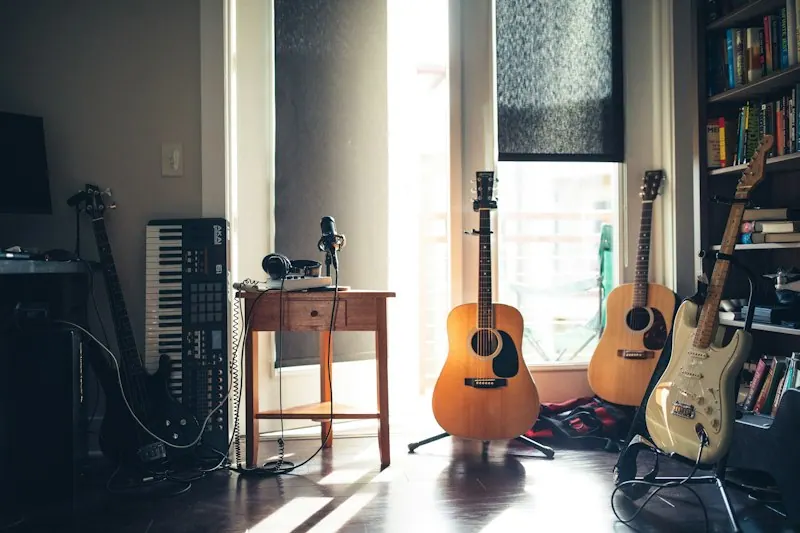 窓辺の明るい部屋に並んだ3本のギターと鍵盤